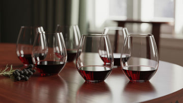 Elegant stemless wine glasses on a wooden table with red wine poured